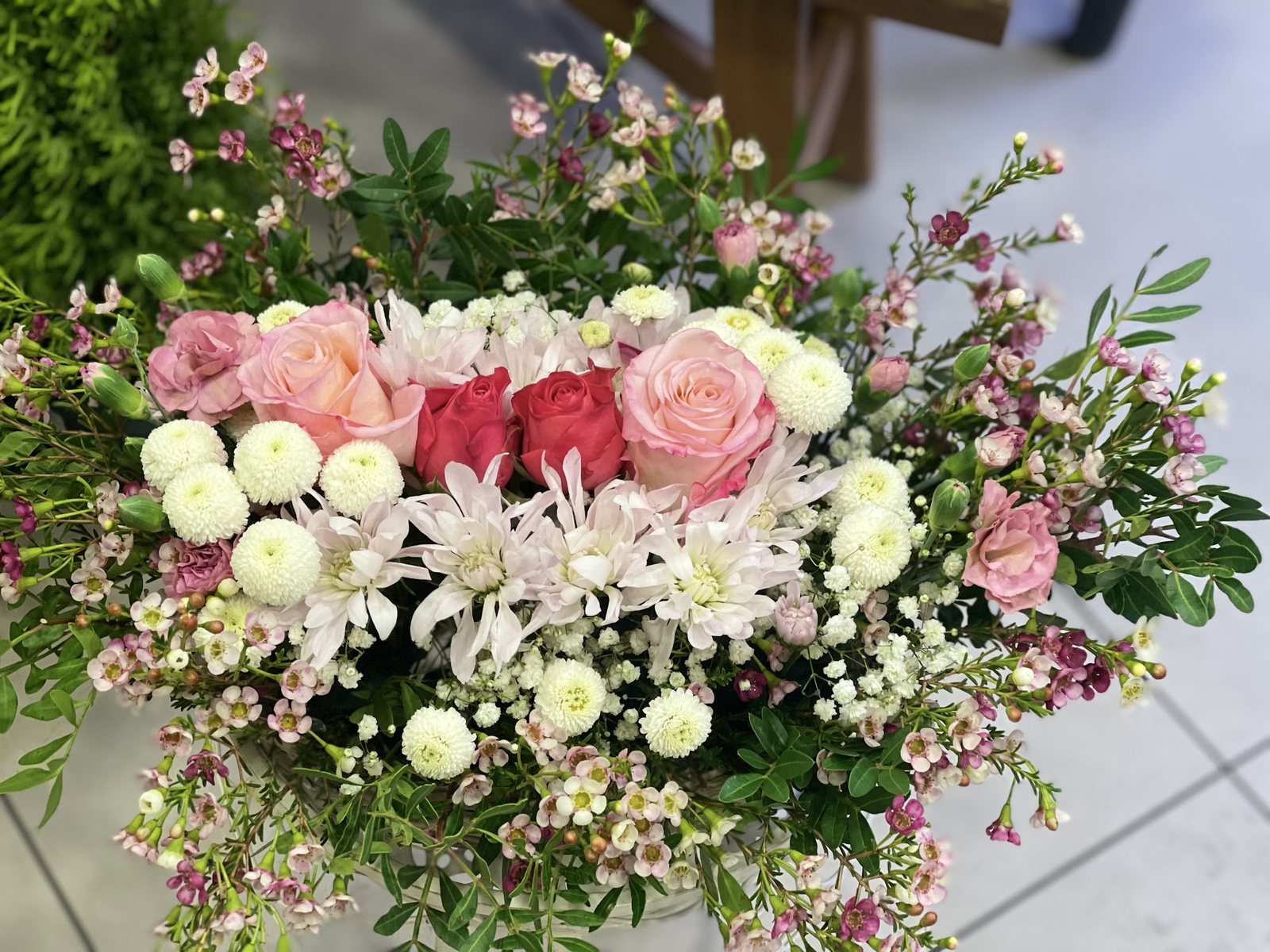 Composition longue de roses, chrysanthèmes et fleurs de cire